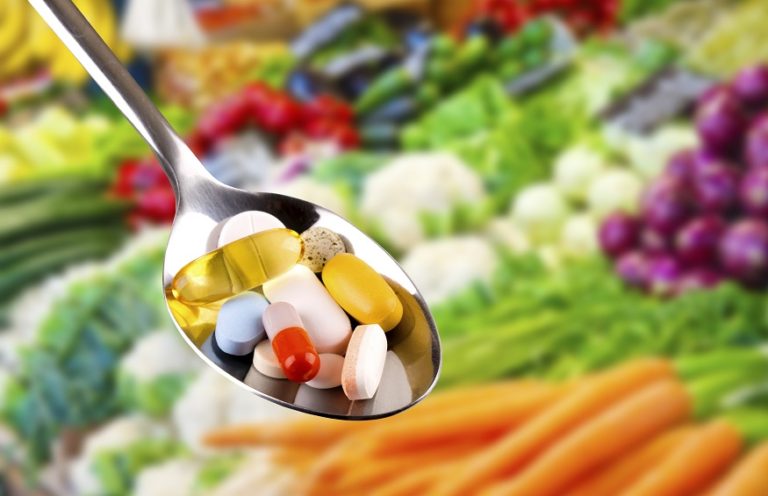 spoon-with-pills-dietary-supplements-on-vegetables-background-health